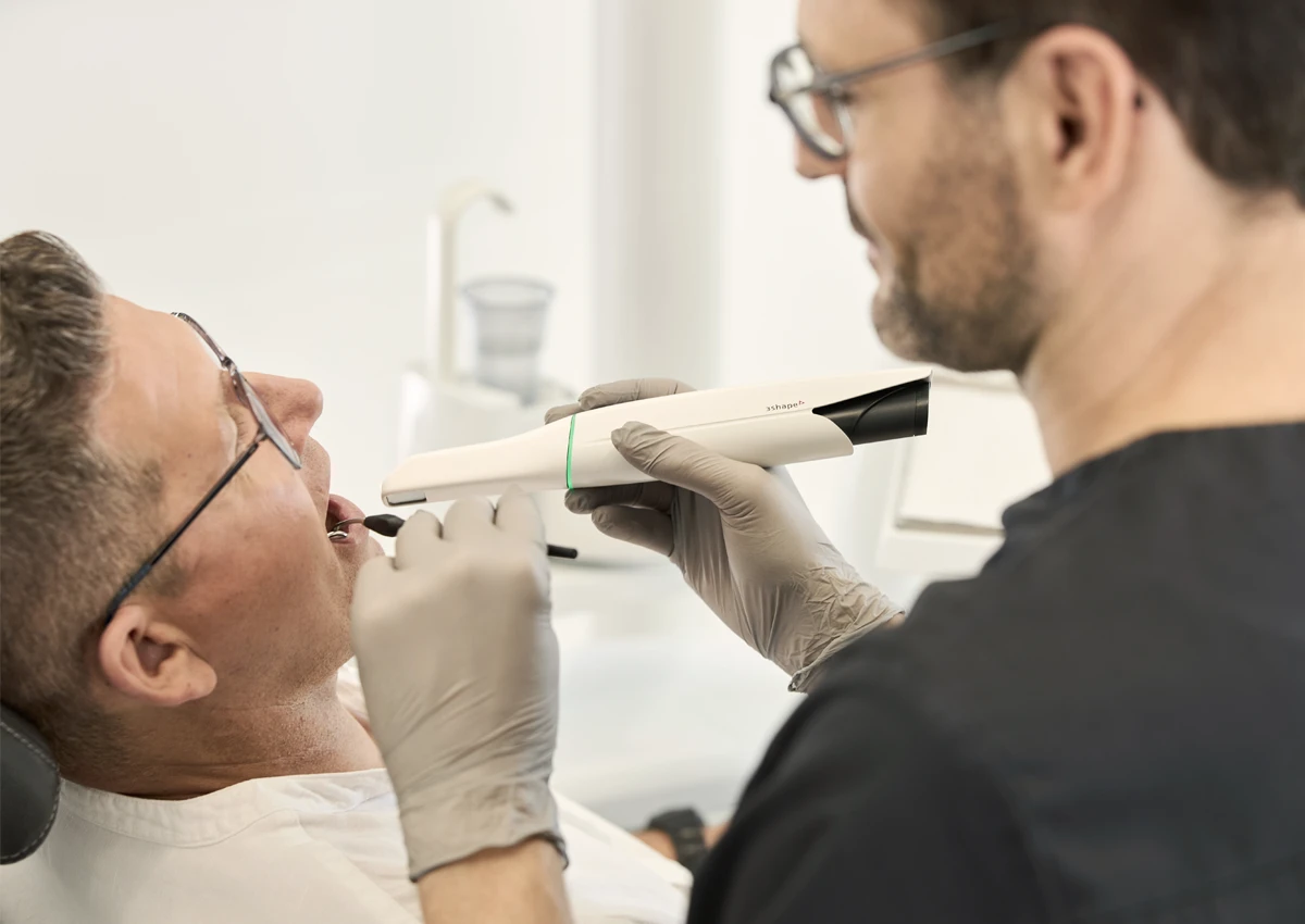 Zahnarzt untersucht Patienten mit speziellem Intraoralscanner in moderner Praxisumgebung von Dr. Rothacher & Kollegen.