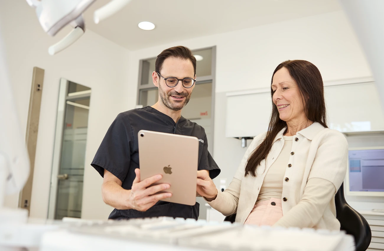 Zahnarzt Dr. Rothacher mit iPad erklärt Patientin im Behandlungszimmer eine Diagnose.