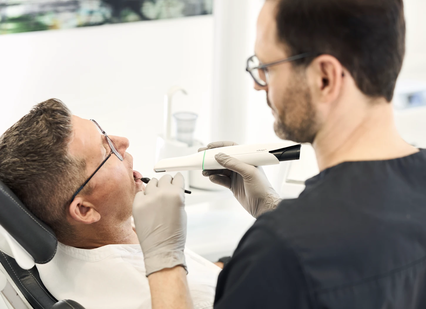 Zahnarzt untersucht Patient mit modernem Oralscanner in Praxis von Dr. Rothacher in Grünkraut.