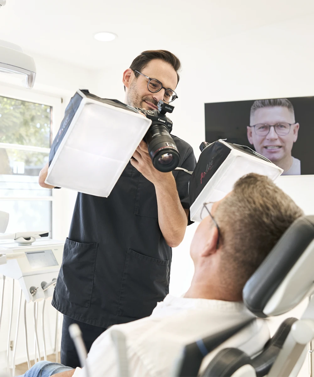 Zahnarzt macht Fotos von einem Patienten im Behandlungsstuhl, Praxis Dr. Rothacher & Kollegen in Grünkraut.