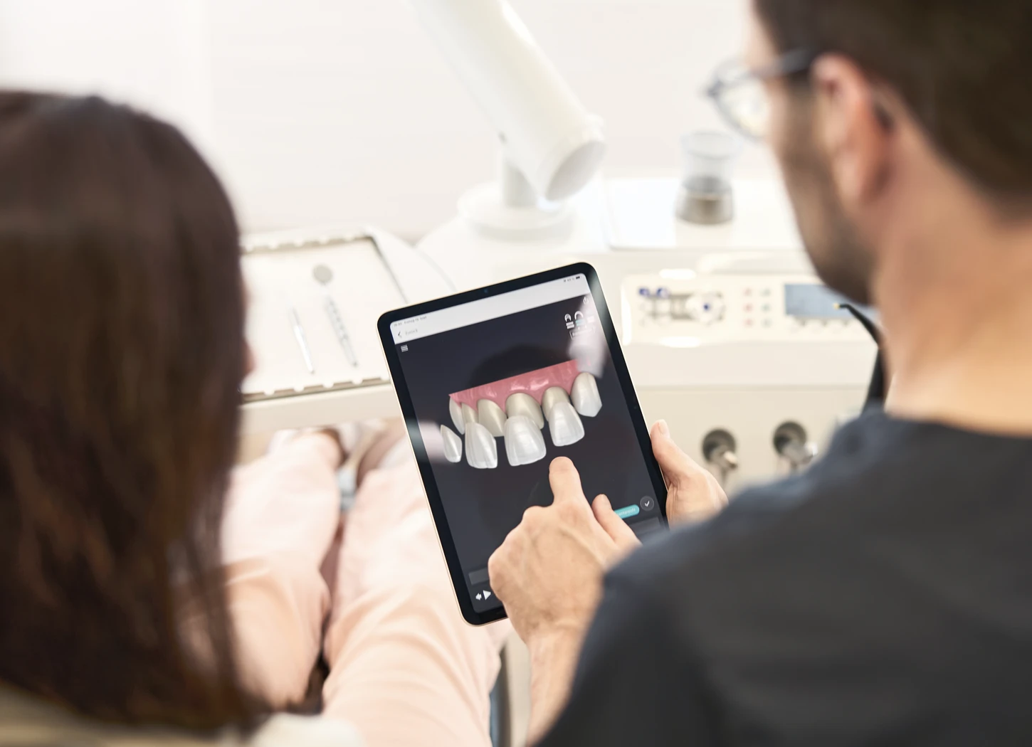 Zahnarzt zeigt Patient digitale Zahnabbildung mit Veneers auf Tablet in moderner Praxis.